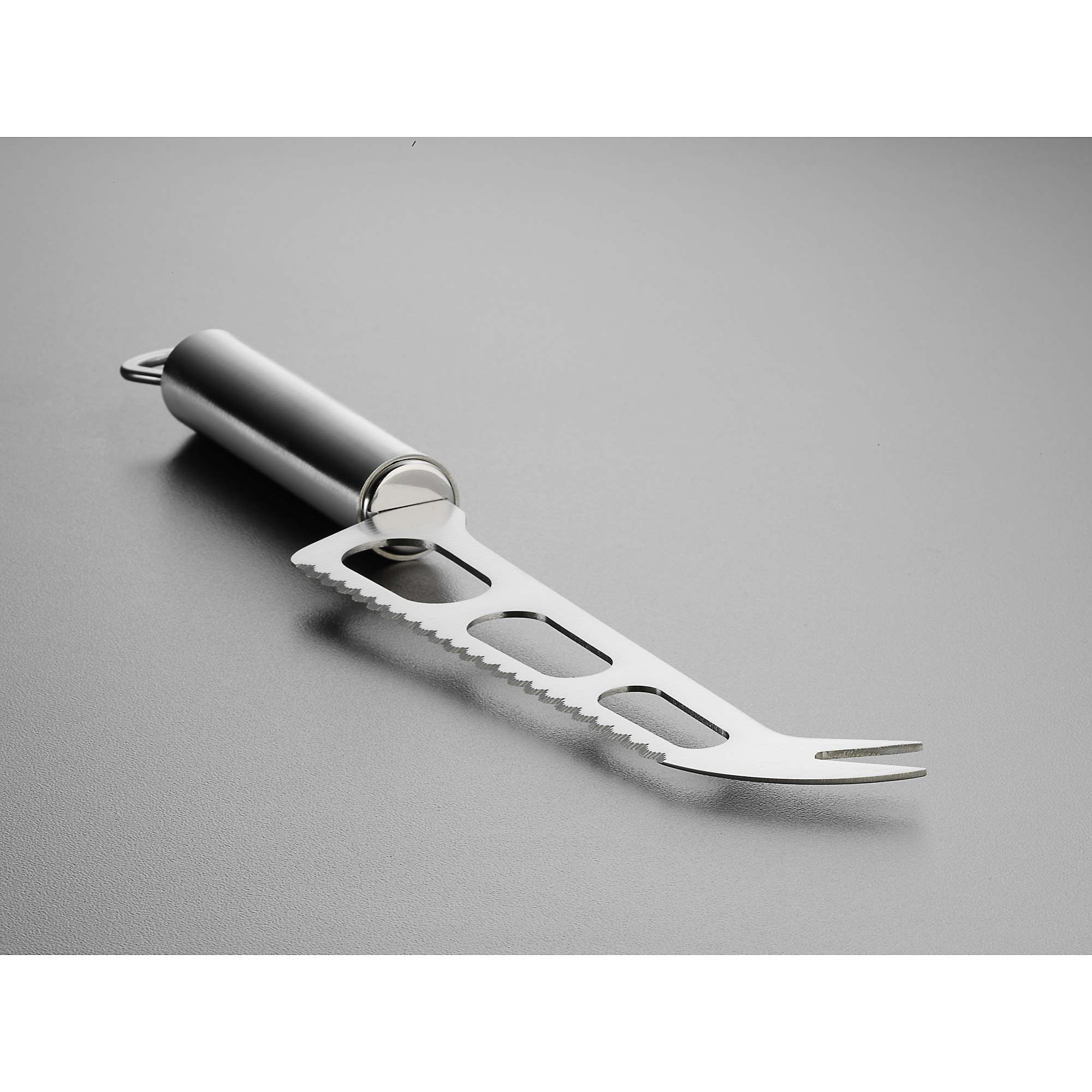 Silbernes Käsemesser mit gezahnter Klinge und Griff auf grauer Oberfläche.