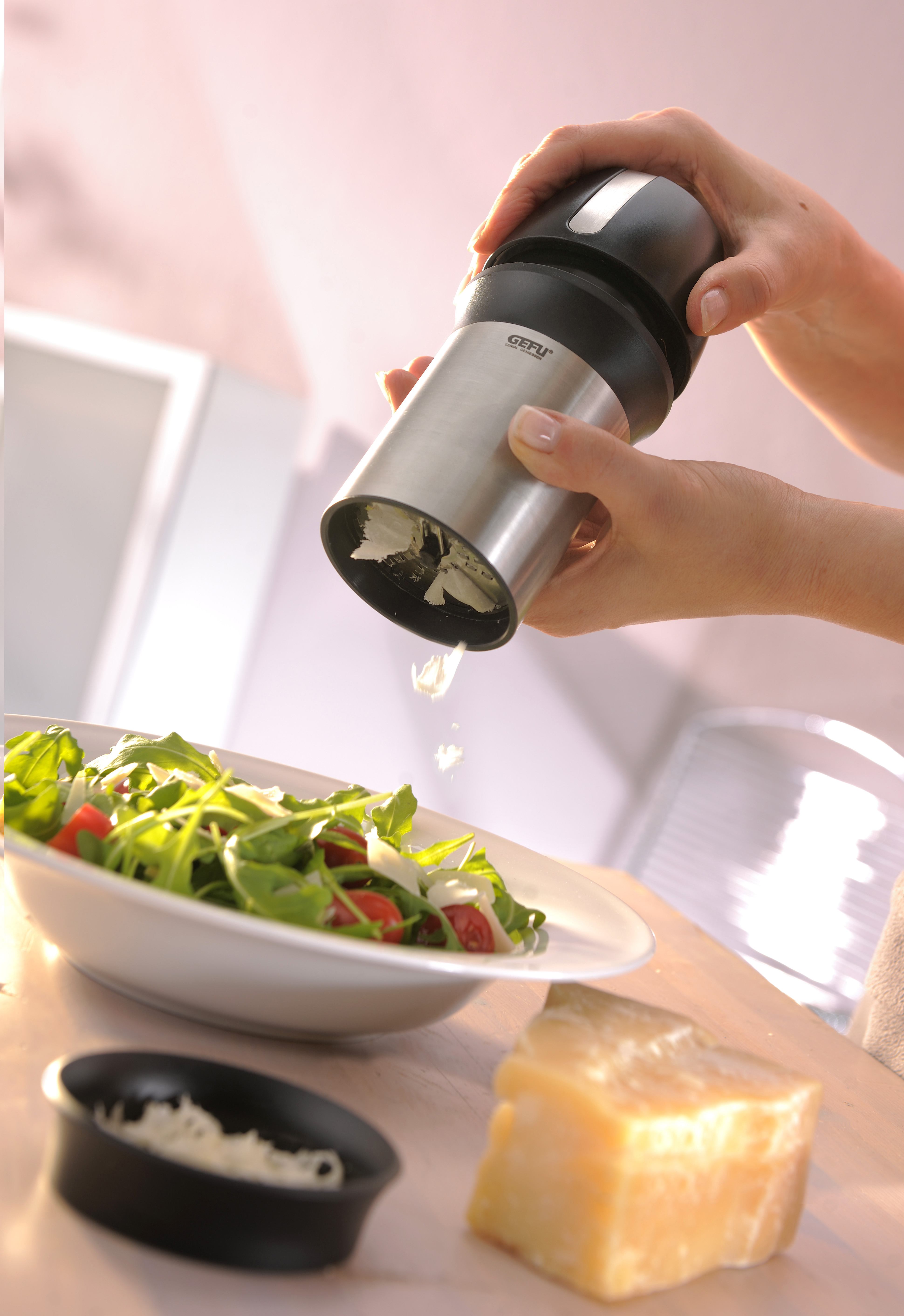 Person reibt Käse über Salat mit Parmesanblock.