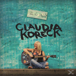 Albumcover von Claudia Koreck mit Gitarre. Der Hintergrund ist eine türkisfarbene Wand, mit 'Home Jam'-Schild.