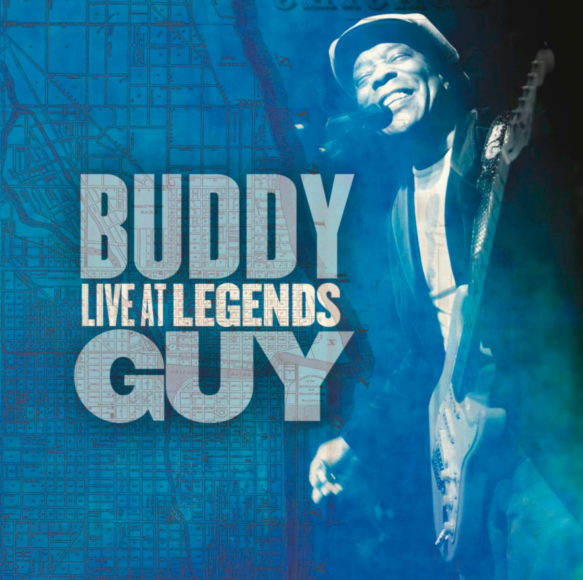 Buddy Guy auf einem Konzertposter. Es zeigt einen lächelnden Mann mit Gitarre, Stadtplan-Hintergrund und Text.