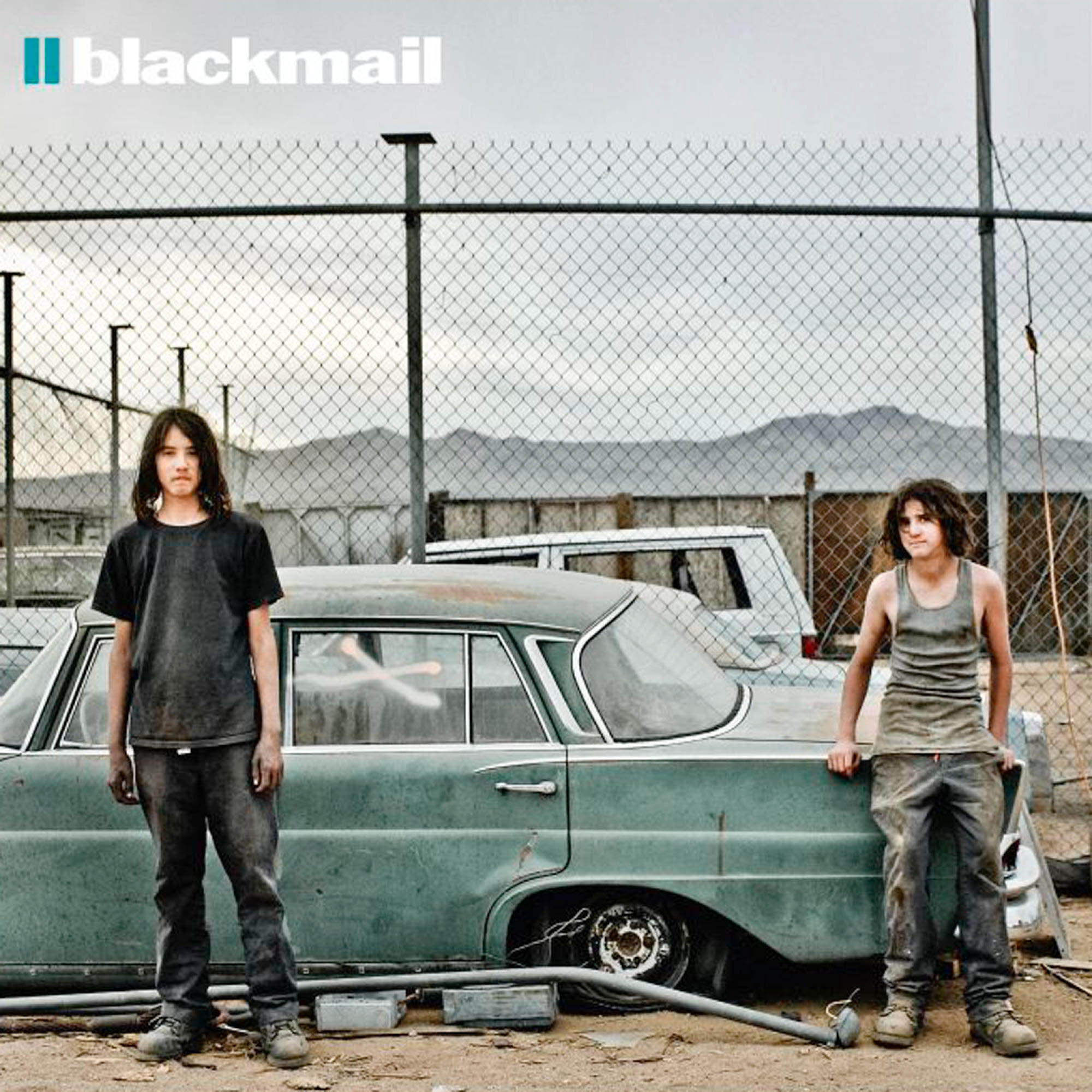 Albumcover: Zwei Jungen lehnen an einem Auto, Zaun und Landschaft im Hintergrund. Titel: II Blackmail.