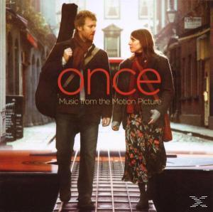 Zwei Personen, ein Mann mit Gitarrenkoffer und eine Frau, gehen durch eine Stadt. Der Titel lautet "Once".