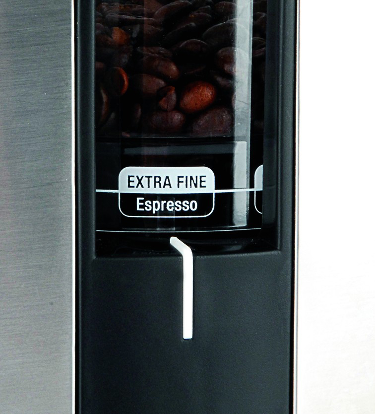 Nahaufnahme einer Kaffeemaschinenkomponente mit Kaffeebohnen und Text 'EXTRA FINE Espresso'.