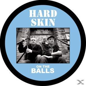 Hard Skin-Albumcover. Drei Männer sitzen auf Stufen. Der Albumtitel in weißen Blockbuchstaben auf einem hellblauen Kreis.