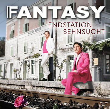 Zwei Männer in Anzügen stehen und sitzen in der Nähe eines Bahngleises. Gebäude und Text 'FANTASY' sind im Hintergrund.