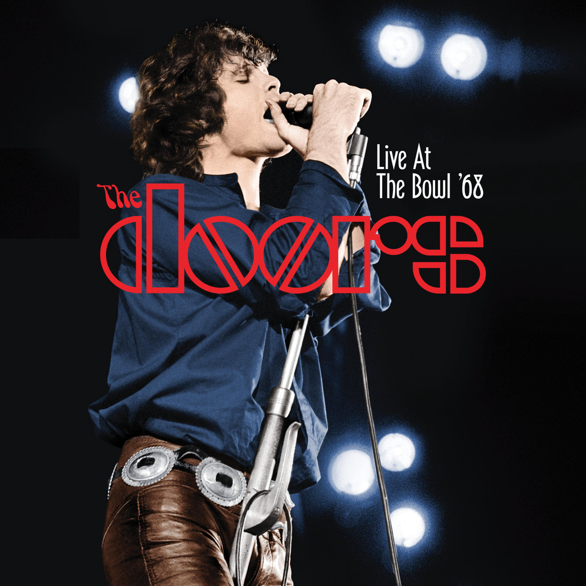 Jim Morrison singt in ein Mikrofon auf einer Bühne, mit 'The Doors' Logo oben.