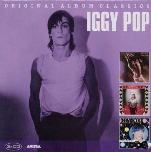 Iggy Pop Albumcover. Mann in weißem T-Shirt steht vor einer lila Wand, neben Albumcovern.