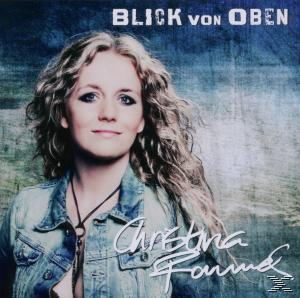 Blonde Frau mit welligem Haar, trägt eine Jeansjacke, schaut in die Kamera, mit Textüberlagerung.
