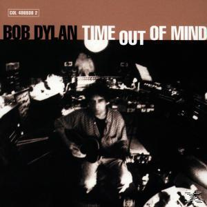 Bob Dylan spielt Gitarre in einem dunklen Raum; Studioausrüstung im Hintergrund.