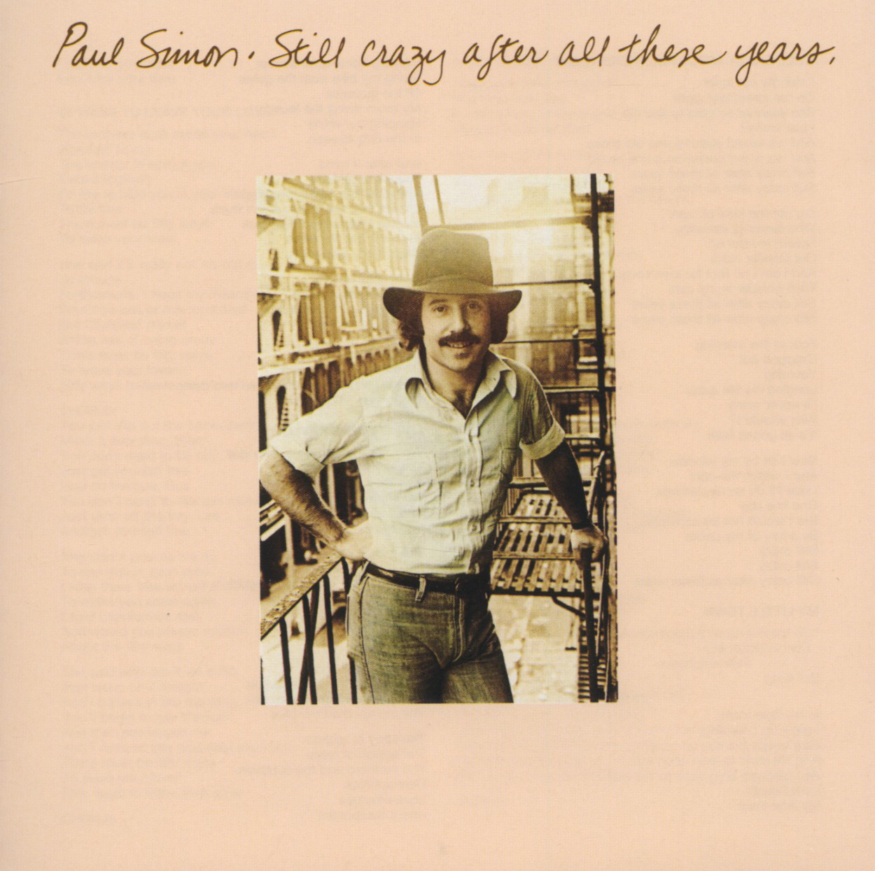Paul Simon Albumcover. Paul Simon mit Hut, auf einer Feuerleiter stehend, Hände am Geländer.