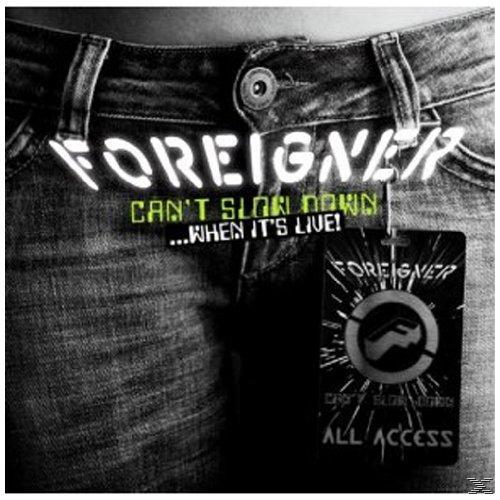 Nahaufnahme von Jeans mit dem Logo der Band Foreigner und Albumdetails auf einem Anhänger. Der Text 'Can't Slow Down'.