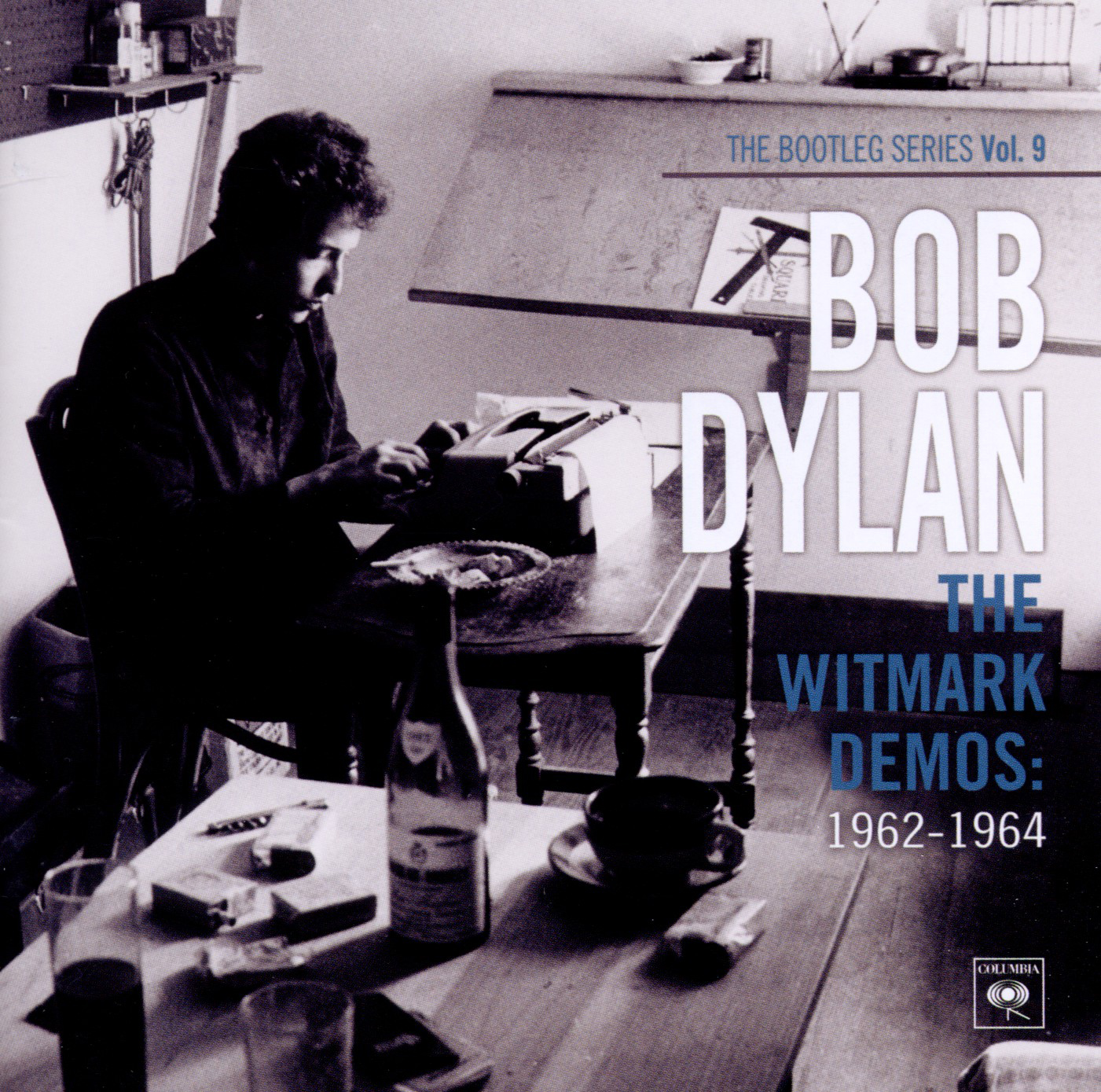 Albumcover: Bob Dylan am Tisch, schreibt. Text: 'The Witmark Demos: 1962-1964' in Schwarzweiß.