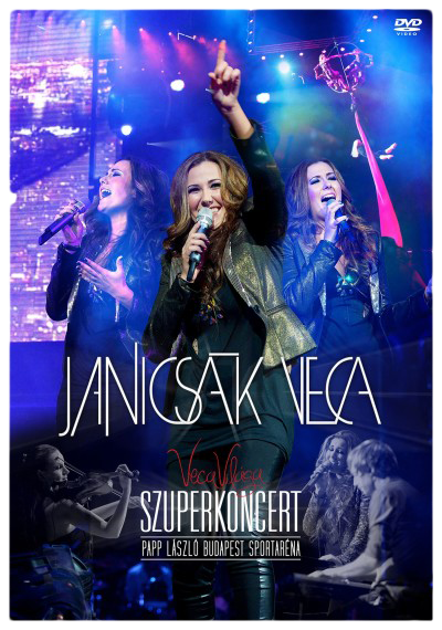 Három énekesnő a színpadon, egyik az ég felé mutat. Koncert háttér fényekkel.