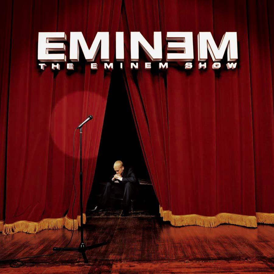 Eminem a színpadon, piros függönyök, reflektor, 'The Eminem Show' albumcím. Sötét és drámai.