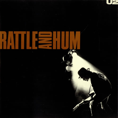 Album borító; U2 együttes tagjai, sötét háttér, reflektor a fellépőkön.