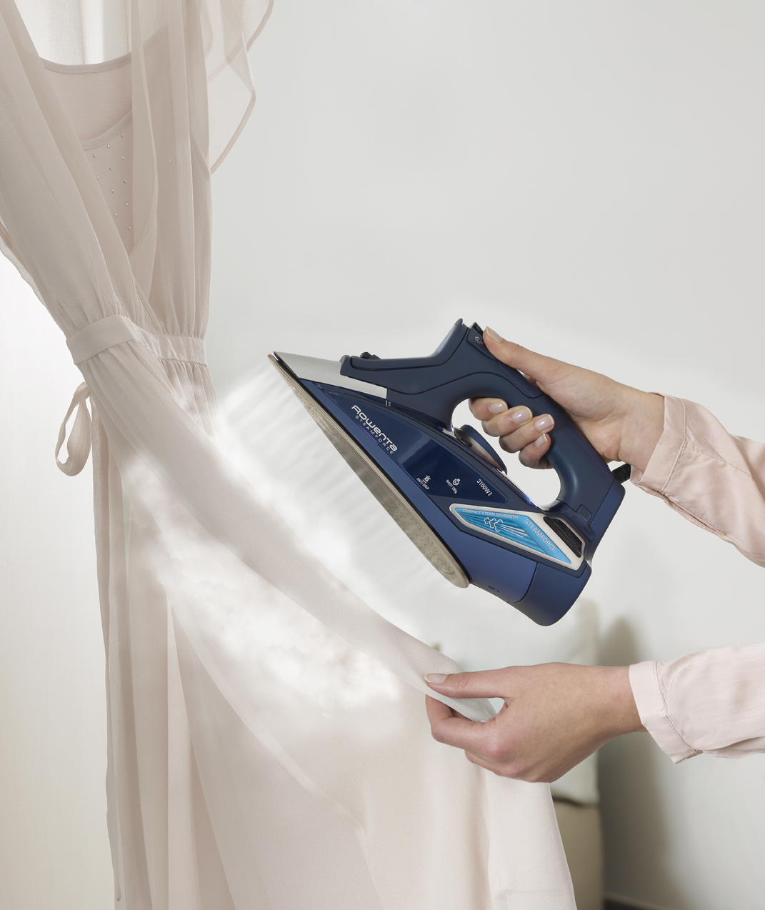 Eine Person bügelt ein Kleid mit einem blauen Bügeleisen, Dampf kommt heraus.