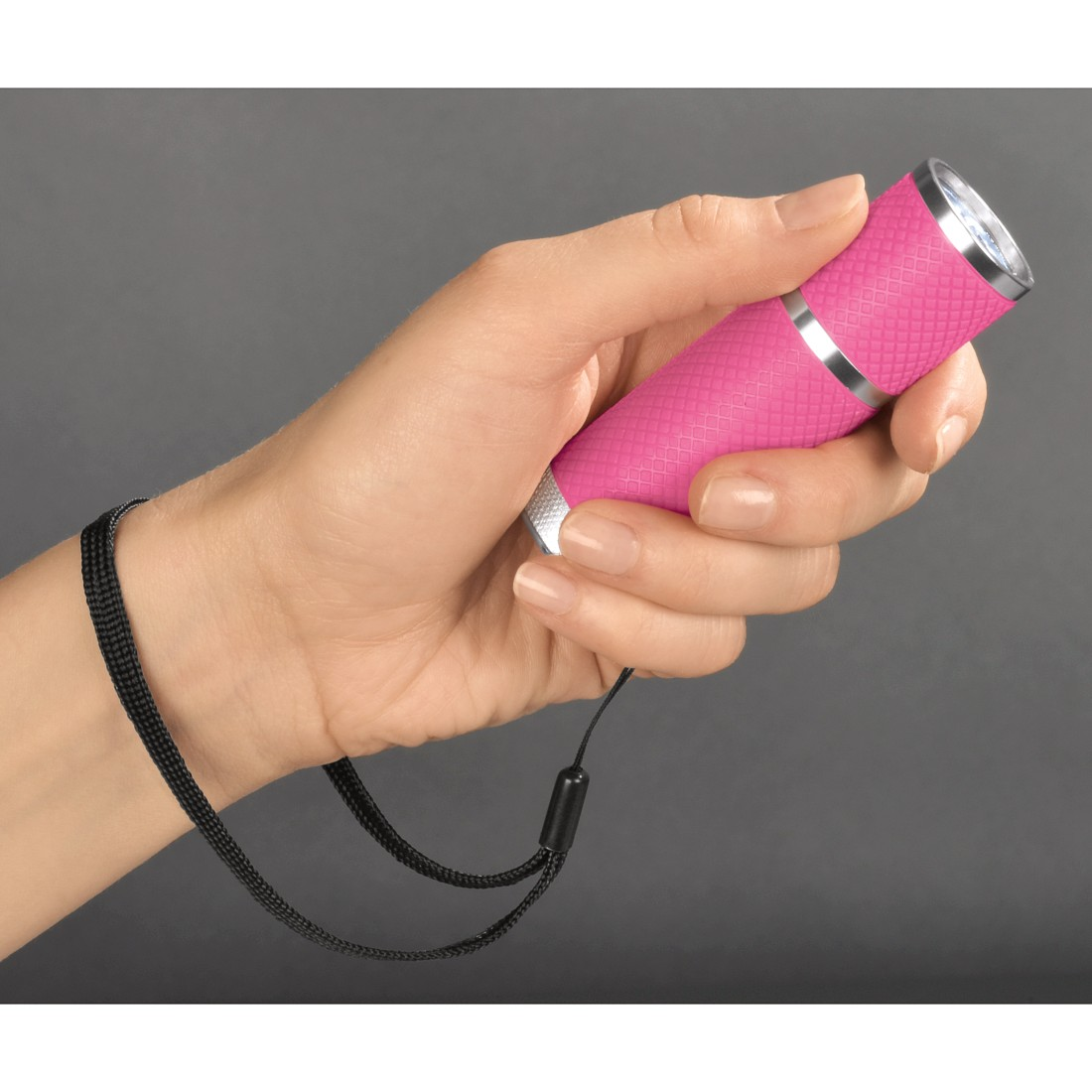 Eine Hand, die eine rosa Taschenlampe mit einem schwarzen Handgelenksriemen hält. Der Hintergrund ist dunkelgrau.