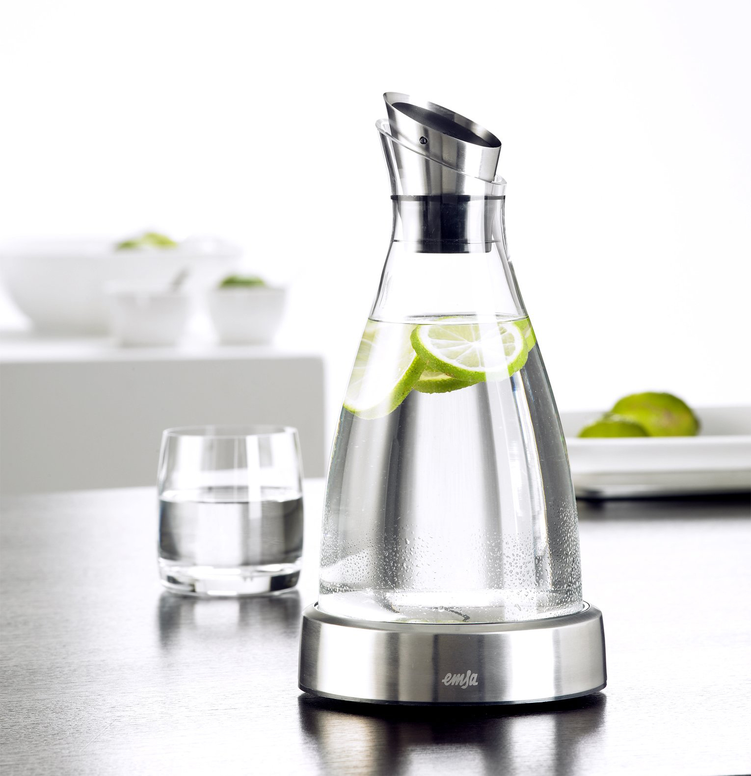 Glaskaraffe mit Limetten und einem Glas. Weißer Hintergrund.