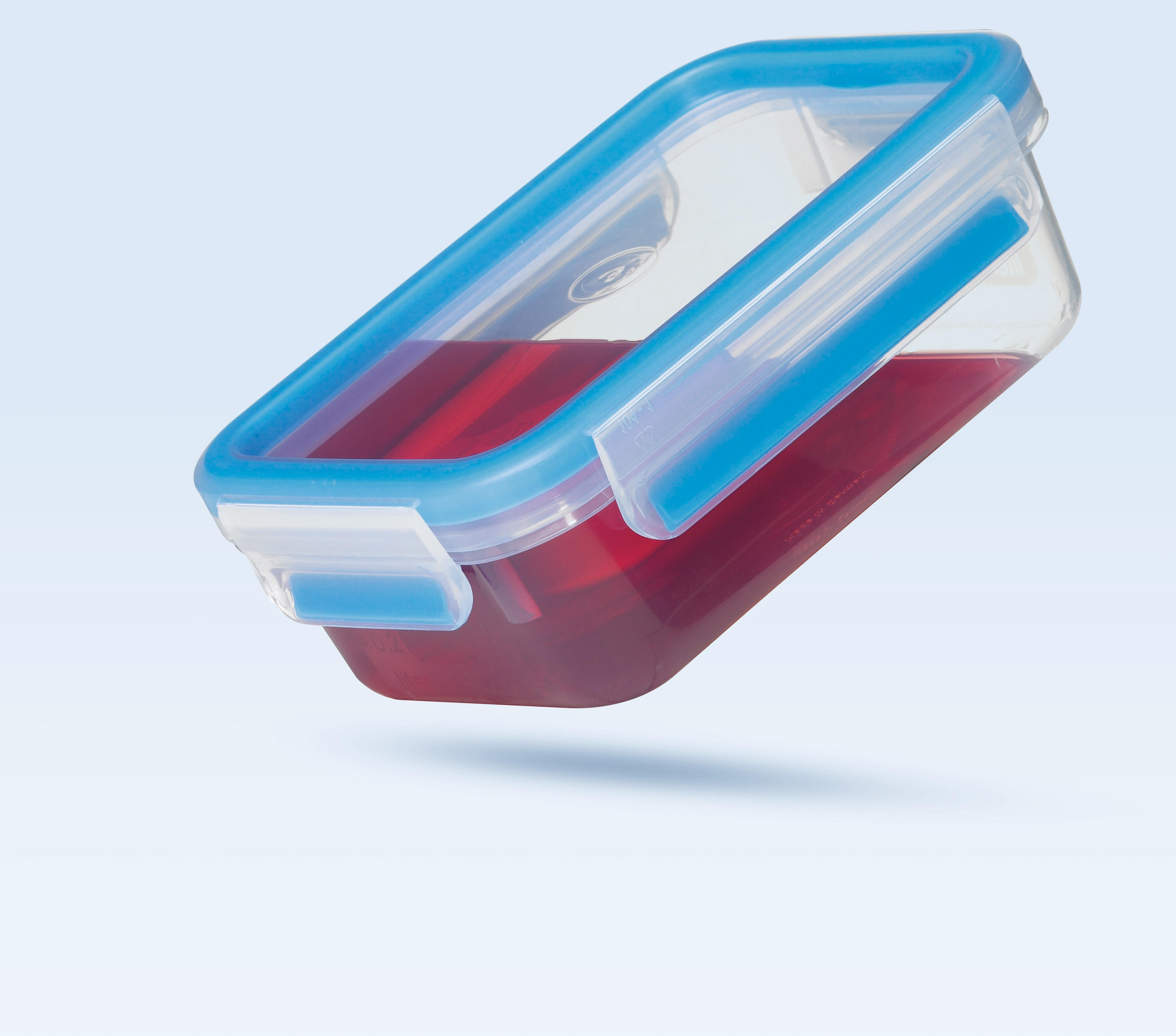 Ein klarer rechteckiger Behälter mit blauem Deckel, gefüllt mit roter Flüssigkeit. Der Behälter ist schräg.