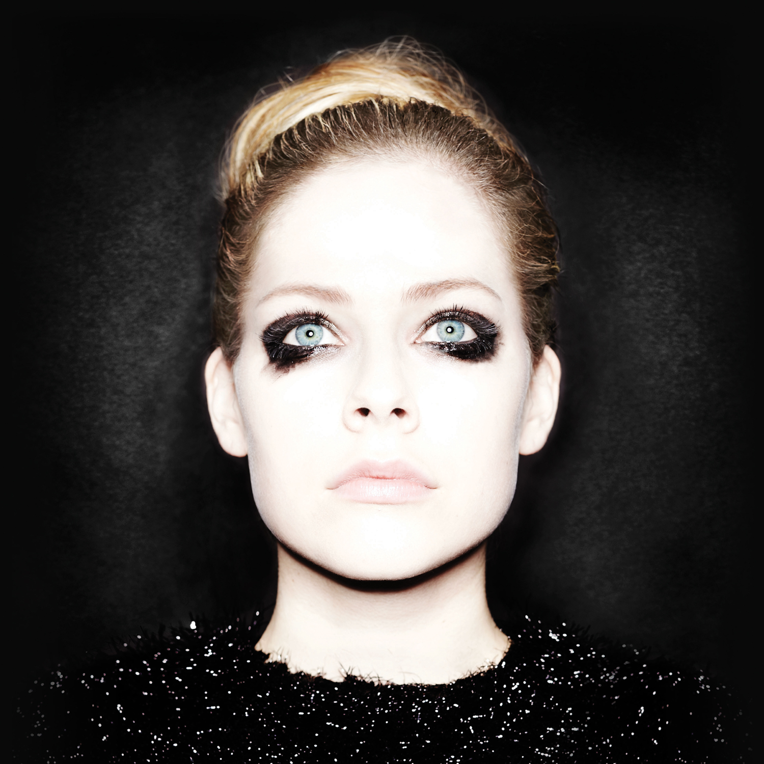 Blonde Frau mit dunklem Make-up um die Augen, blickt in die Kamera.