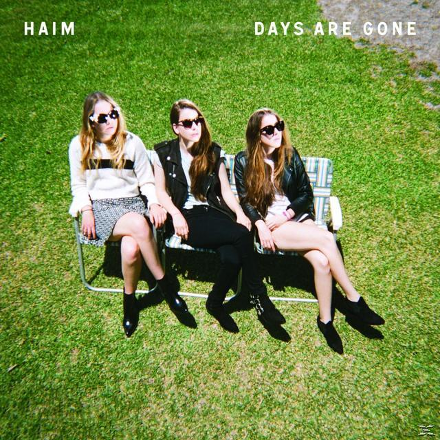 Drei Frauen mit Sonnenbrillen sitzen auf einer Bank auf Gras. Albumtitel 'Days Are Gone'.