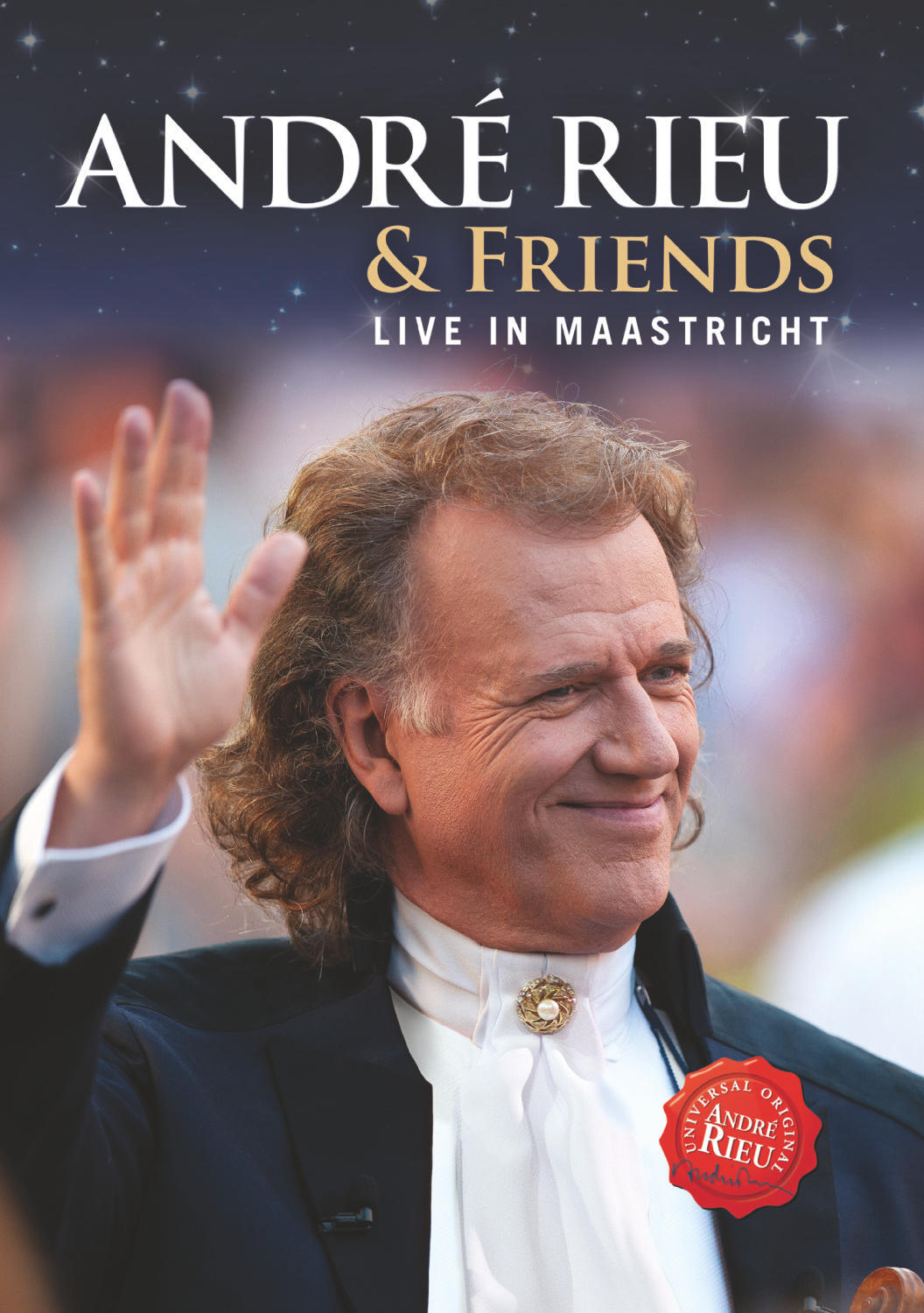 André Rieu winkt, lächelt. Er trägt einen schwarzen Anzug und ein weißes Hemd.
