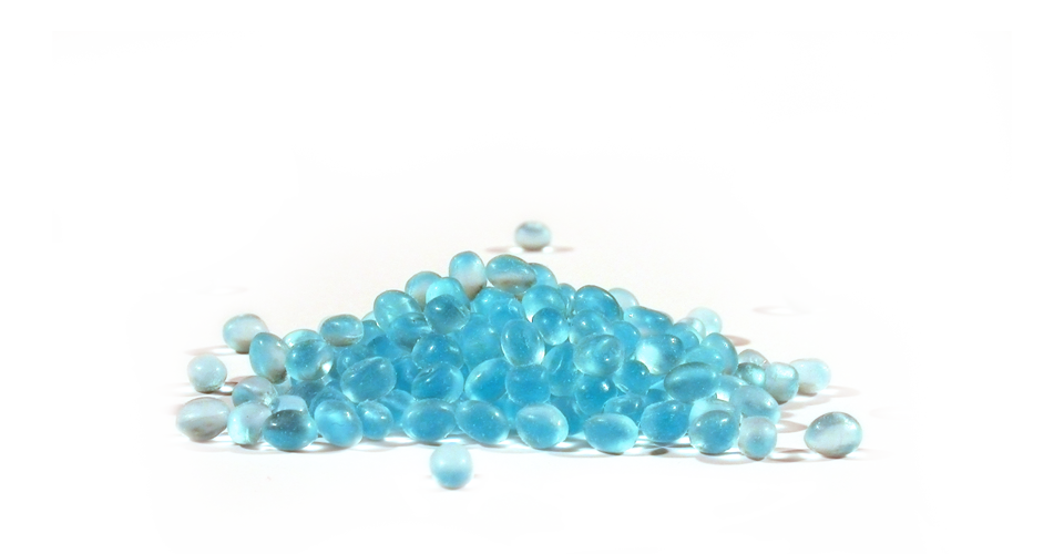 Pila di perle blu su superficie bianca, con alcune sparse.