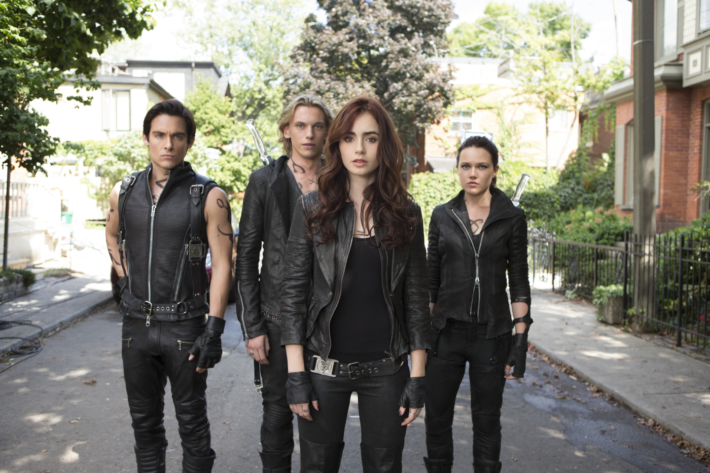 The Mortal Instruments Cover. Vier Personen in schwarzem Leder stehen auf einer Straße und halten Waffen.