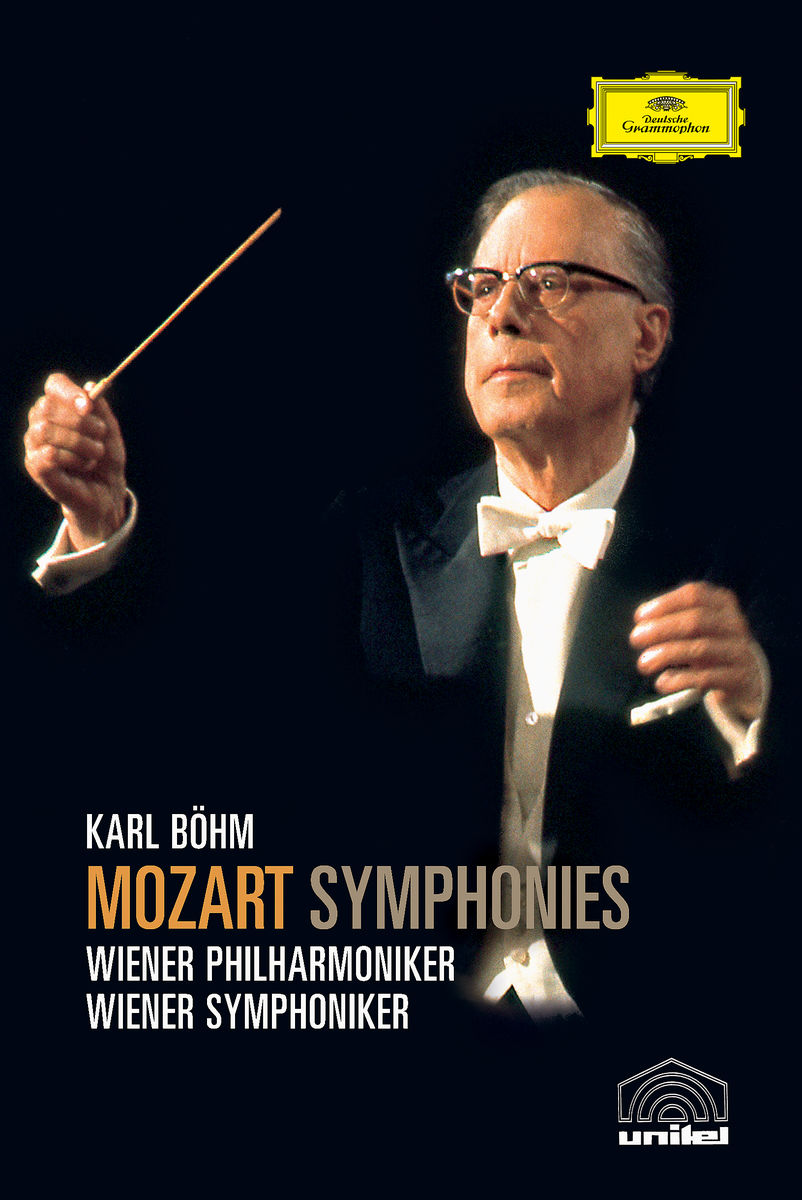 Ein Dirigent mit Brille, hält einen Taktstock und dirigiert ein Orchester.