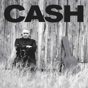 Schwarz-Weiß-Bild von Johnny Cash, der sich an eine Holzwand lehnt.