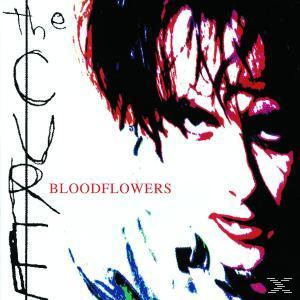 Albumcover: Gesicht mit roten Lippen, schwarze Haare, weißer Hintergrund, Text 'Bloodflowers'.