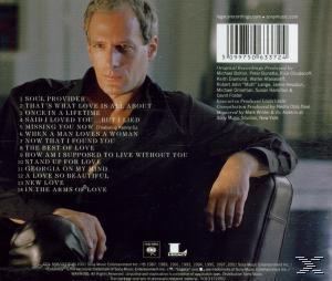 Mann in schwarzem Hemd sitzt auf einem Stuhl. Albumcover mit Songtiteln im Hintergrund.