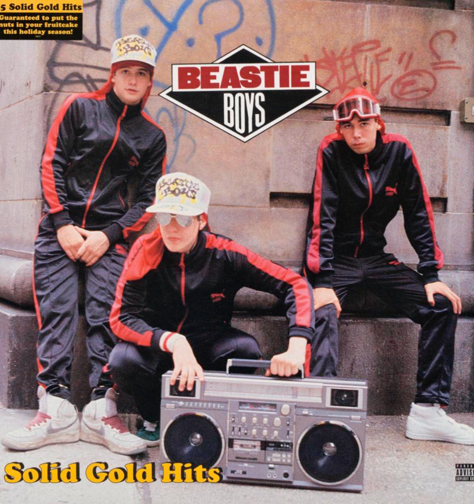 Beastie Boys Albumcover. Drei Männer in Trainingsanzügen stehen vor einer Graffiti-Wand mit einer Boombox.