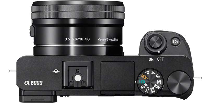 Draufsicht auf eine schwarze Sony α6000 Kamera mit Objektiv. Verschiedene Knöpfe und Räder sind sichtbar.