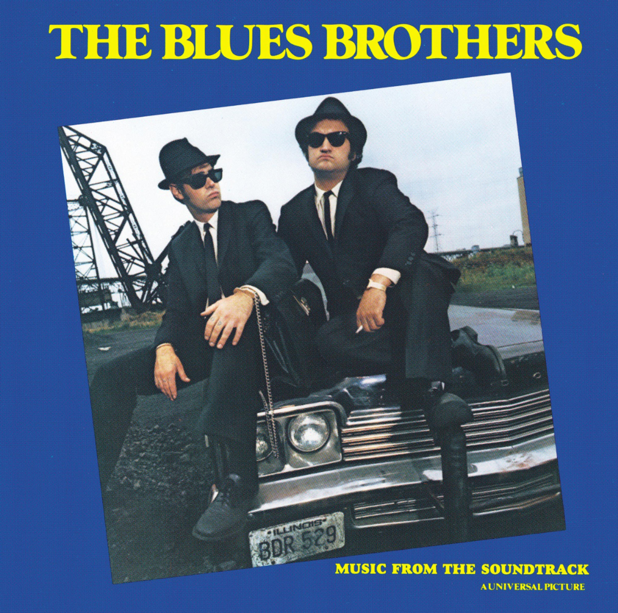 Albumcover von 'The Blues Brothers'. Zwei Männer in schwarzen Anzügen und Hüten, Sonnenbrillen und einem Auto.