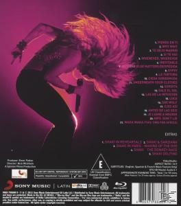 Shakira auf der Bühne. Sie trägt ein schwarz-rosa Outfit, ihre Haare sind rosa. Titelliste ist sichtbar.