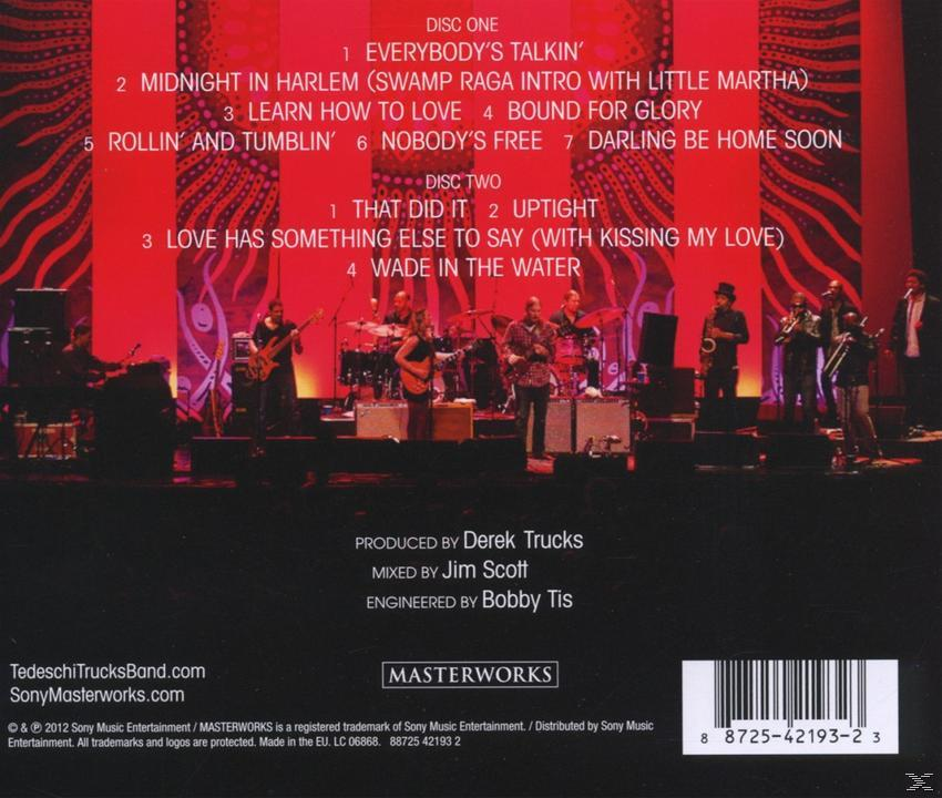 CD-Cover mit Band, Instrumenten und Text auf rotem Hintergrund.