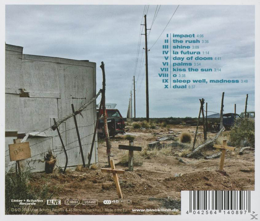 Wüstenlandschaft mit Kreuzen und Strommasten. Links eine Betonmauer. Ein Auto in der Ferne.