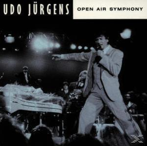 Udo Jürgens auf der Bühne, singt in ein Mikrofon mit einer Band. Schwarzweiß.