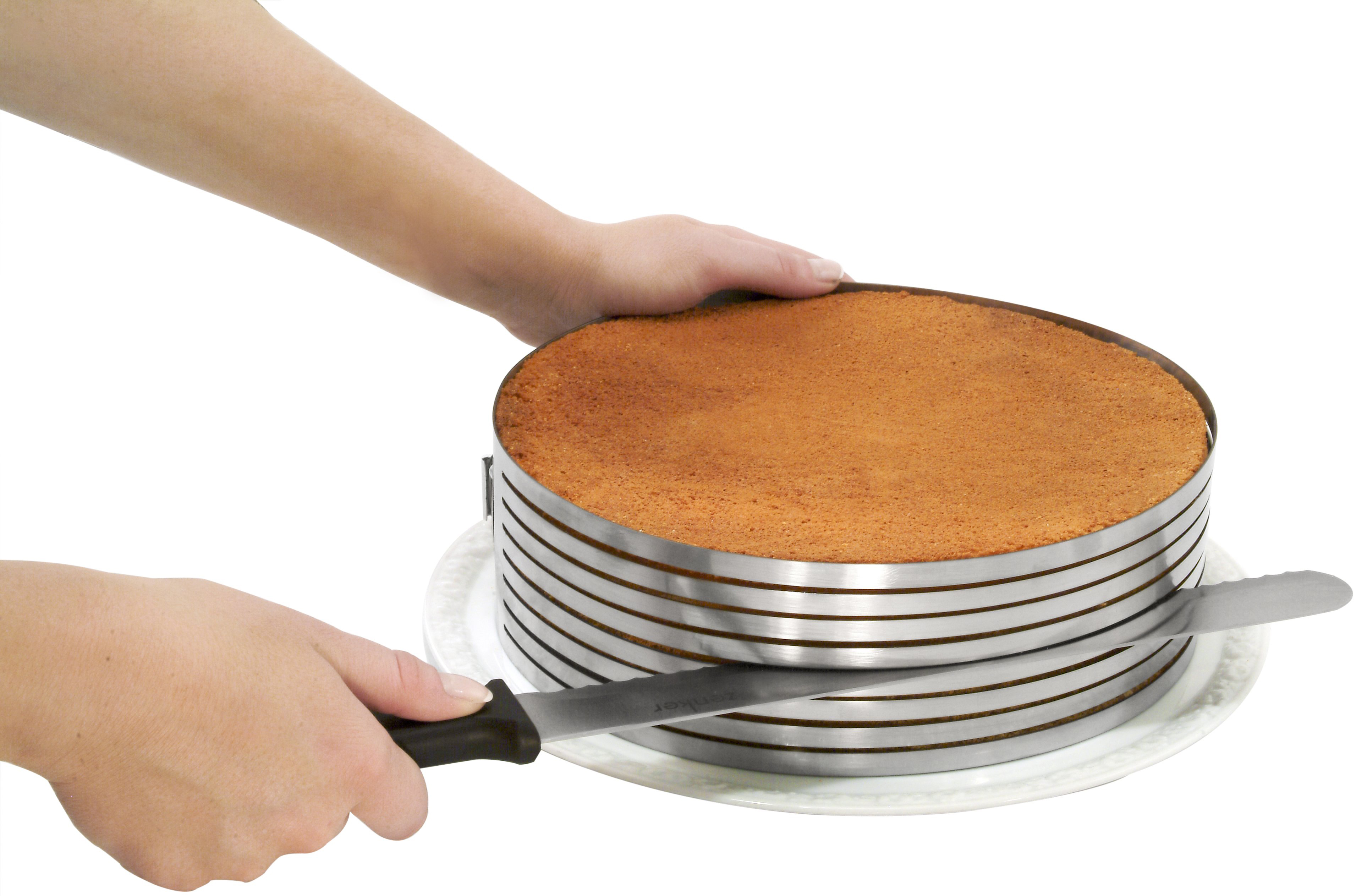 Eine Person schneidet einen Kuchen mit einem speziellen Metallring darum herum.