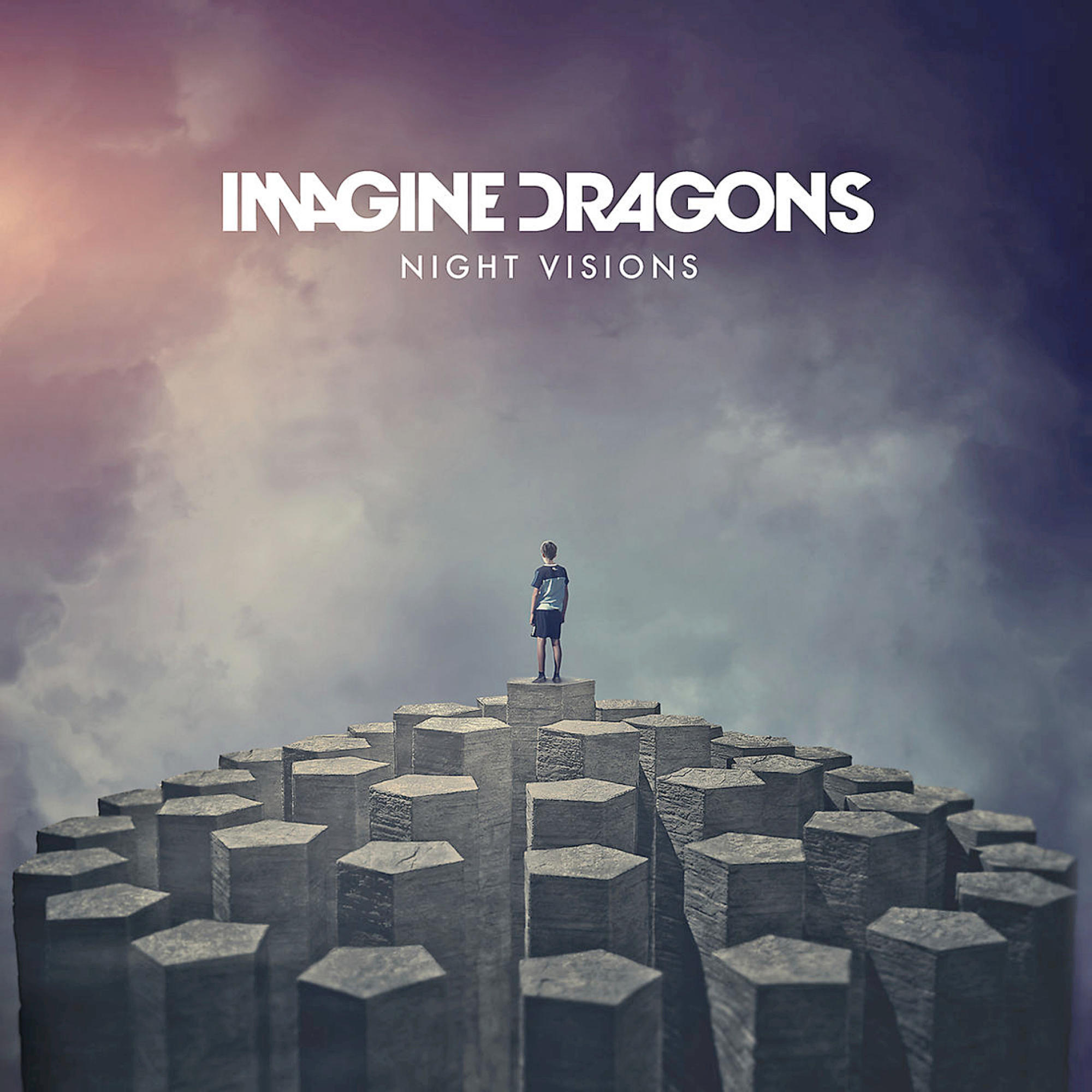 Pochette de l'album 'Imagine Dragons - Night Visions'. Une personne se tient sur une structure en pierre.
