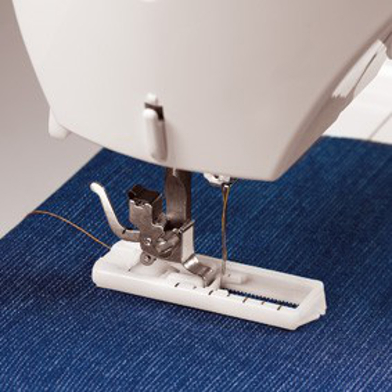Nähmaschinenfuß auf blauem Stoff, Nadel und Faden sichtbar. Maschine ist weiß, Stoff ist Jeans.