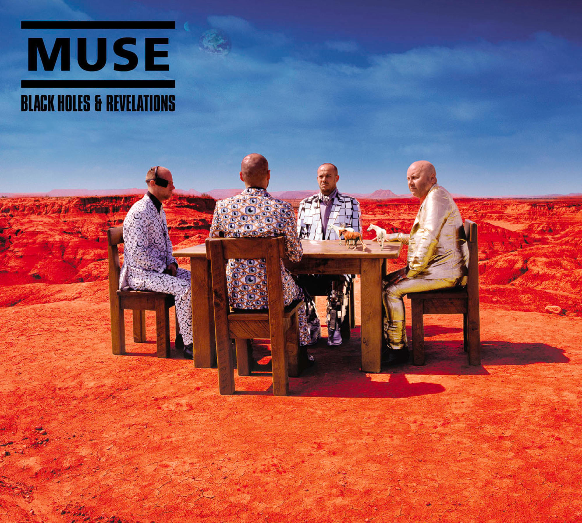 Vier Personen an Tisch auf Mars-ähnlicher Landschaft. Band Muse, Black Holes & Revelations.
