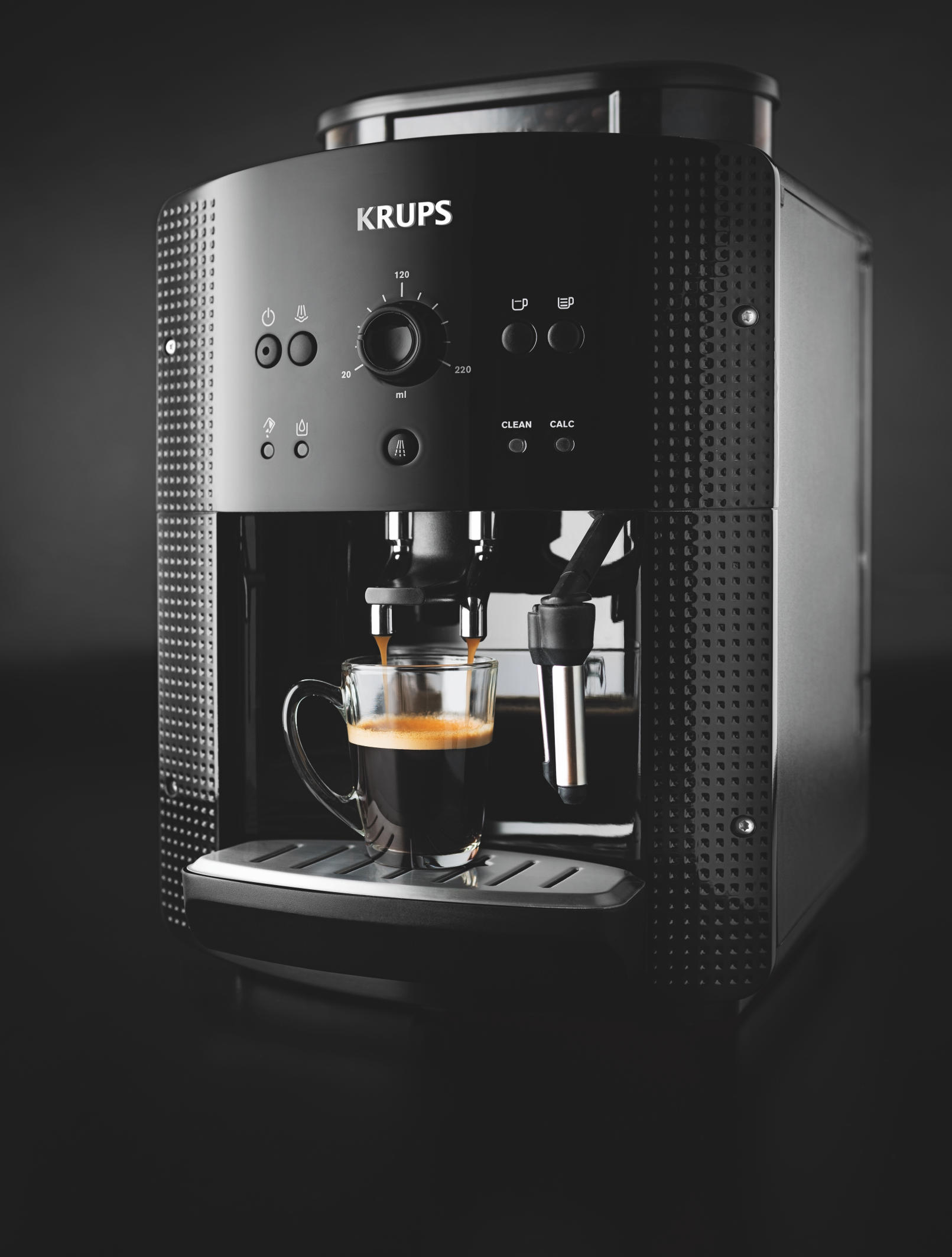 Schwarze Krups Kaffeemaschine, Glasbecher und Espresso.