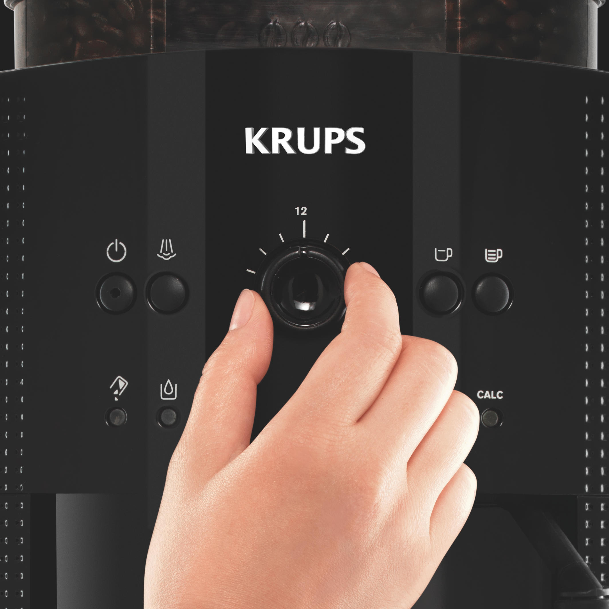 Schwarze Kaffeemaschine, eine Hand stellt den Drehregler ein. KRUPS steht vorne.