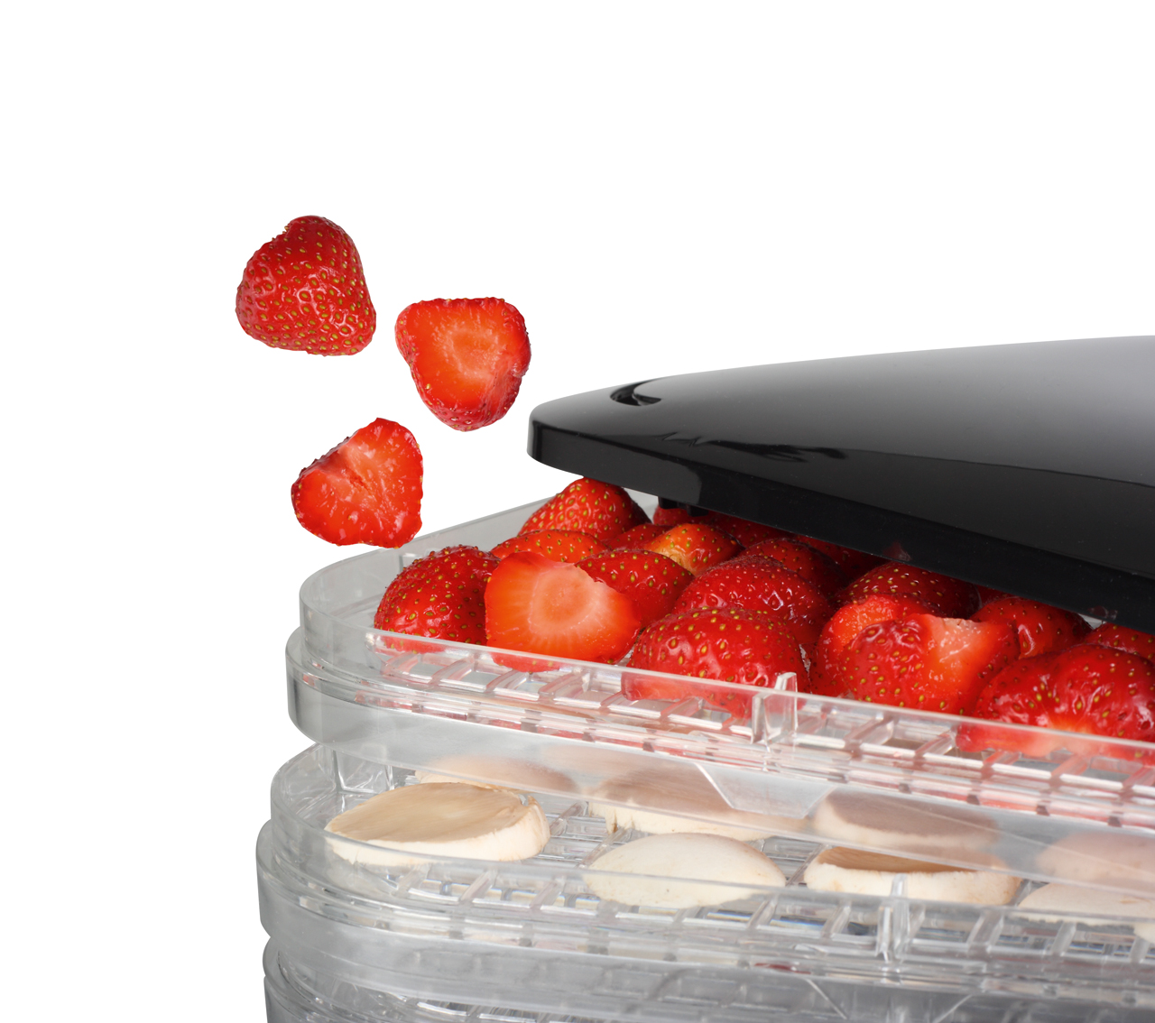 Aardbeien vallen in een voedseldroger, die gesneden fruit bevat.