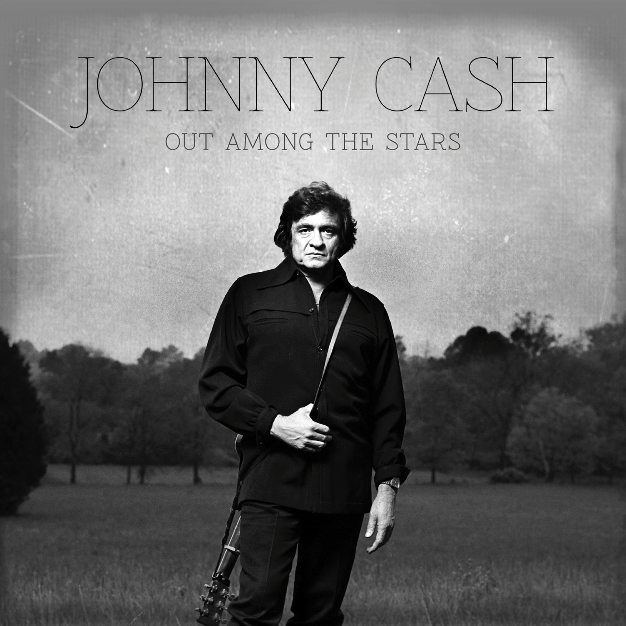 Ein Schwarz-Weiß-Bild von Johnny Cash. Er steht mit einer Gitarre auf einem Feld.