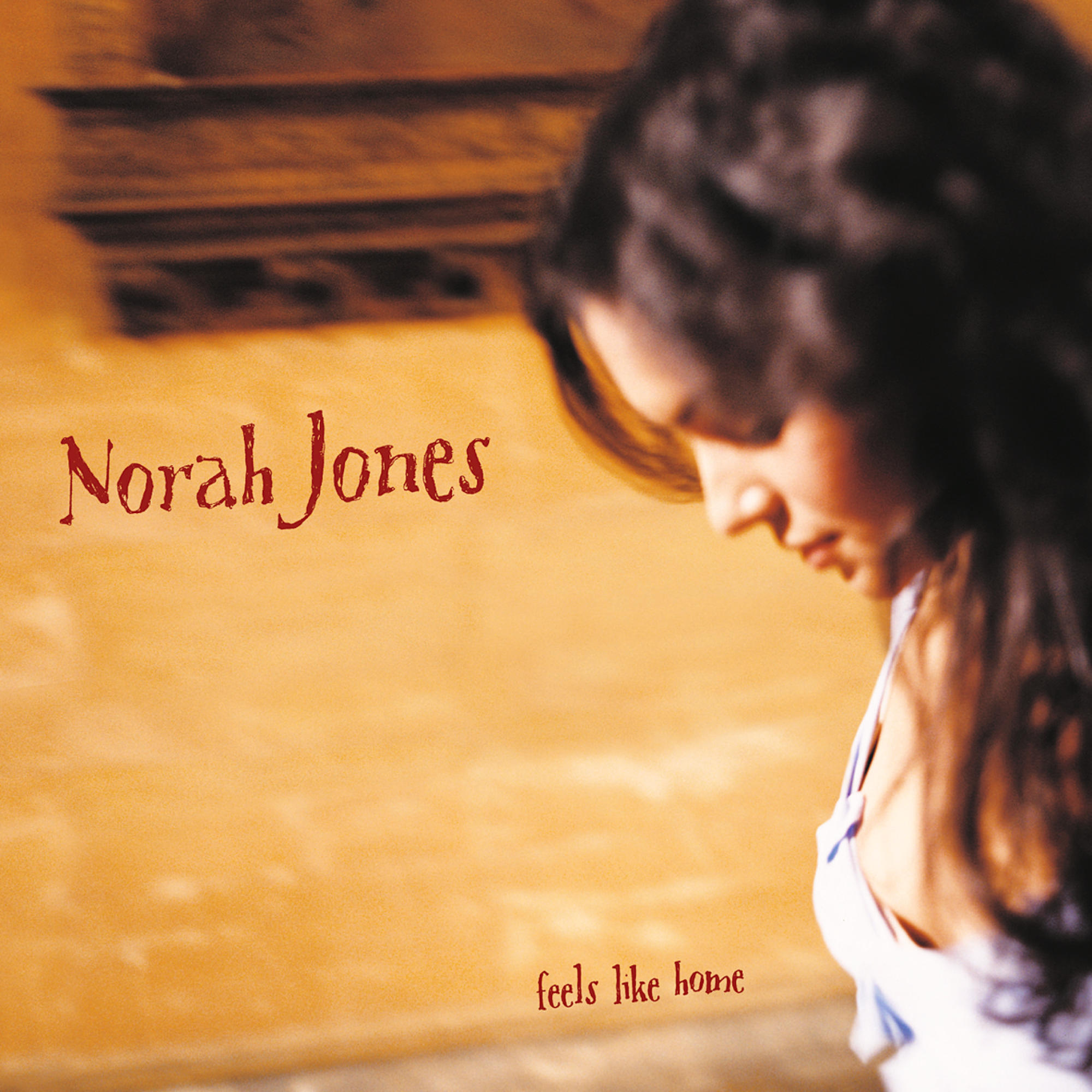 Albumcover von Norah Jones mit ihrem Namen in Rot. Sie ist mit gesenktem Kopf zu sehen, der Titel lautet 'Feels Like Home'.