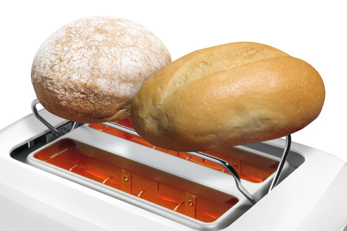 Zwei Brötchen liegen auf einem Toaster. Eines ist rund und braun, das andere oval und hellbraun. Der Toaster ist weiß.