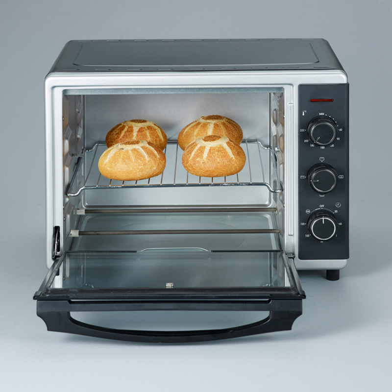 Ein kleiner, geöffneter Toasterofen mit vier gebackenen Brötchen auf einem Rost, mit geöffneter Tür.